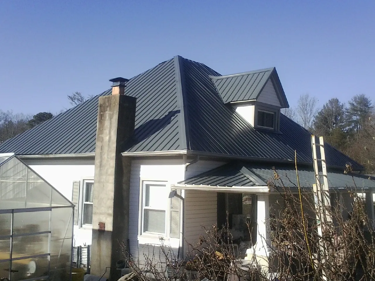 Dark blue standing seam metal roof on a white farmhouse with dormer — Slate & Tile Roof Repair by Roofing Brothers in Weirton