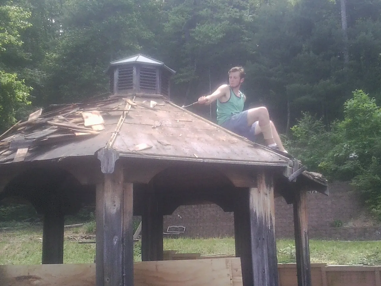 Tearing the old roof off a wooden gazebo before new shakes in Weirton