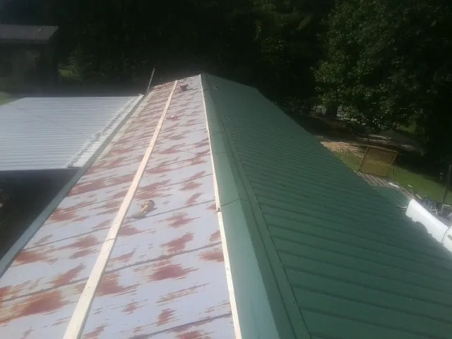 Old rusted panels beside newly installed green metal roofing — Wind Damage Roof Repair by Roofing Brothers in Weirton