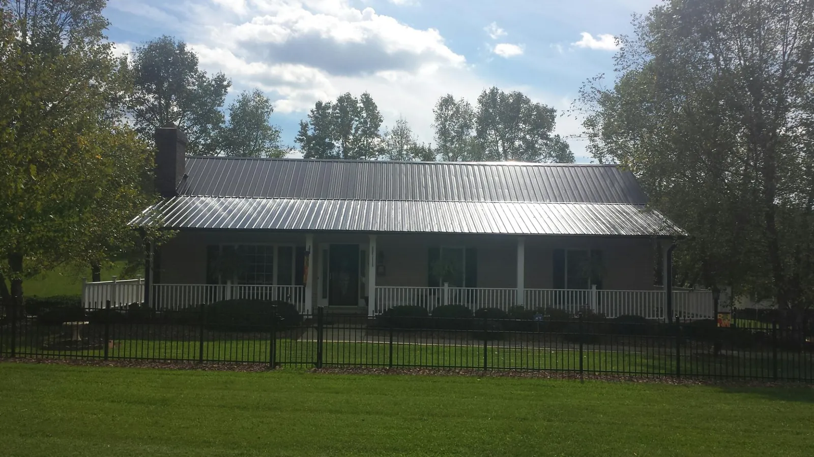 Gray metal roof on a brick ranch with a full width front porch — Gutter Guard Installation work by our crew in Weirton