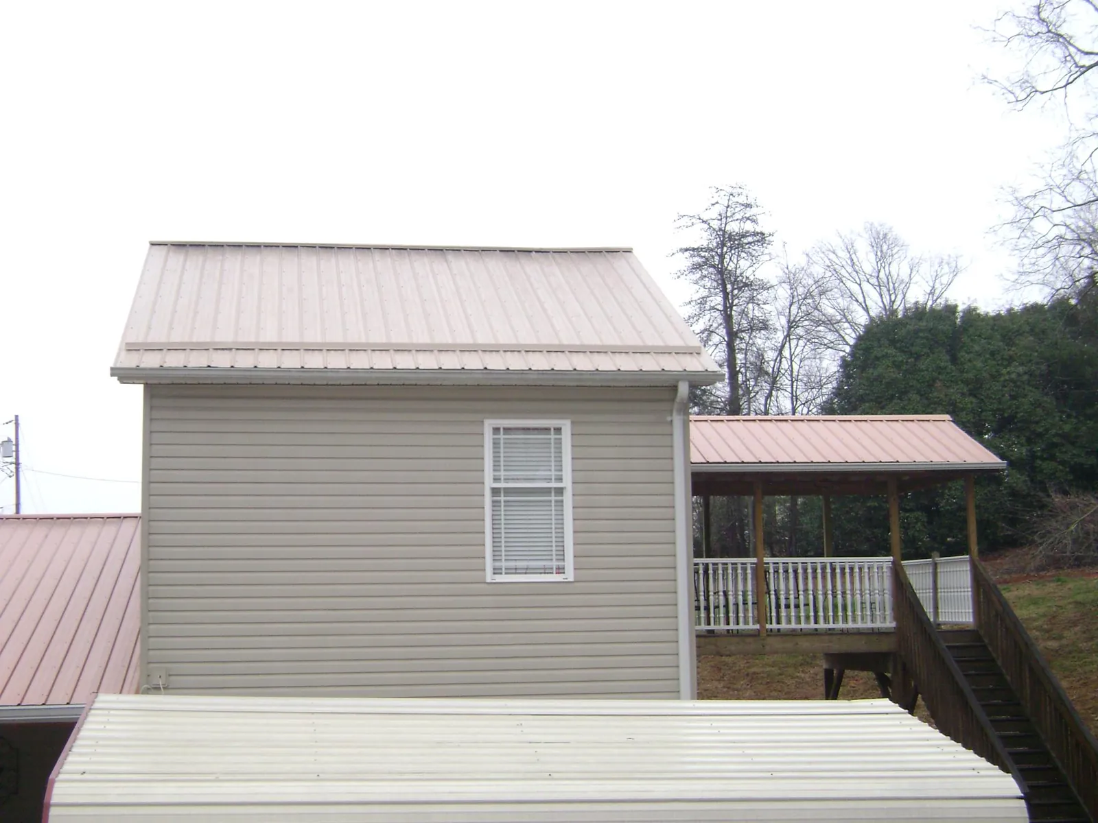 Tan metal roofs on a two story addition and attached porch, from a Roof Replacement job in Weirton