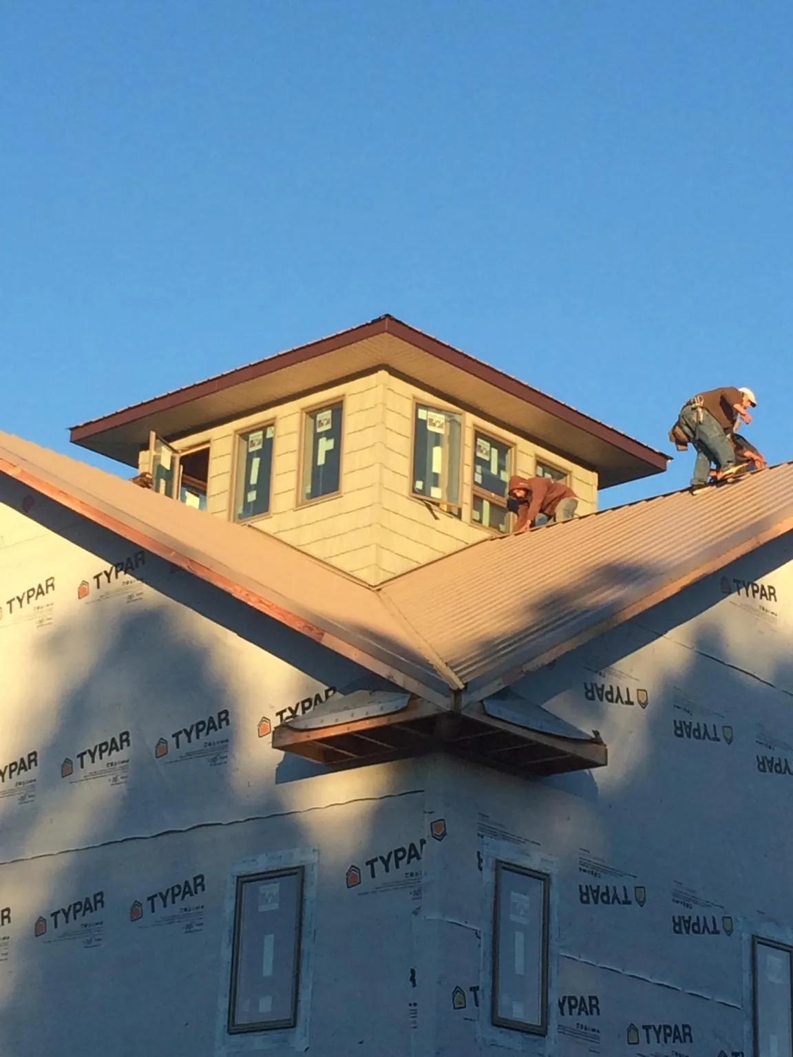 Roofers working around a rooftop cupola on a new metal roof at sunset — Roof Waterproofing in Weirton by Roofing Brothers